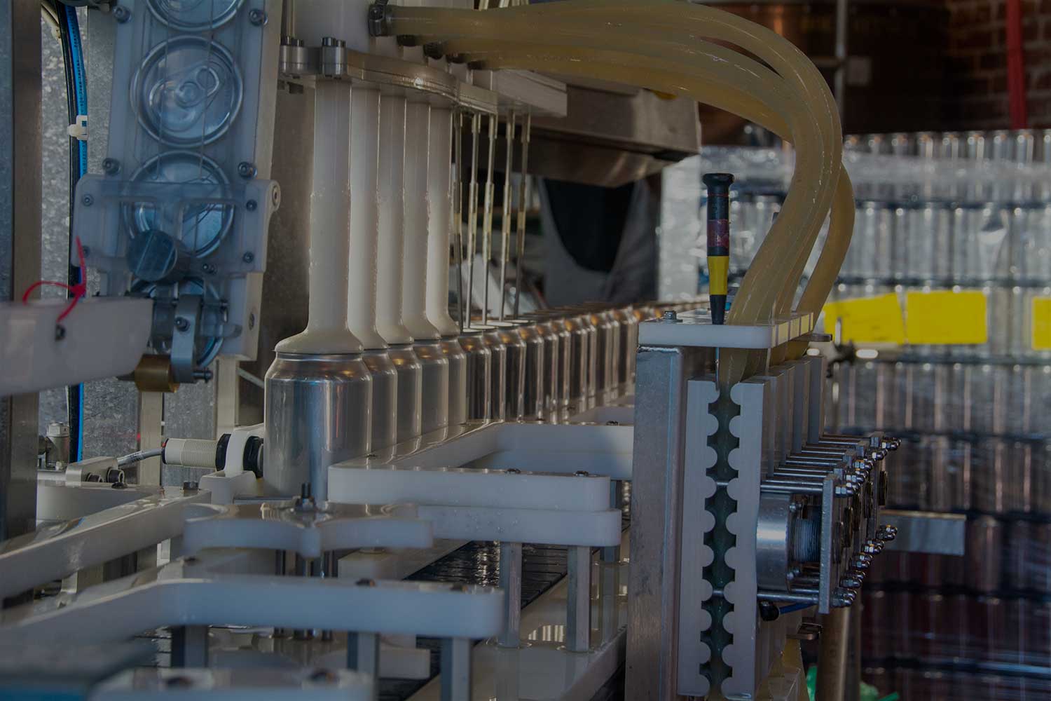 Close-up of beer being poured into cans on the canning line and a pallet of empty cans in the background